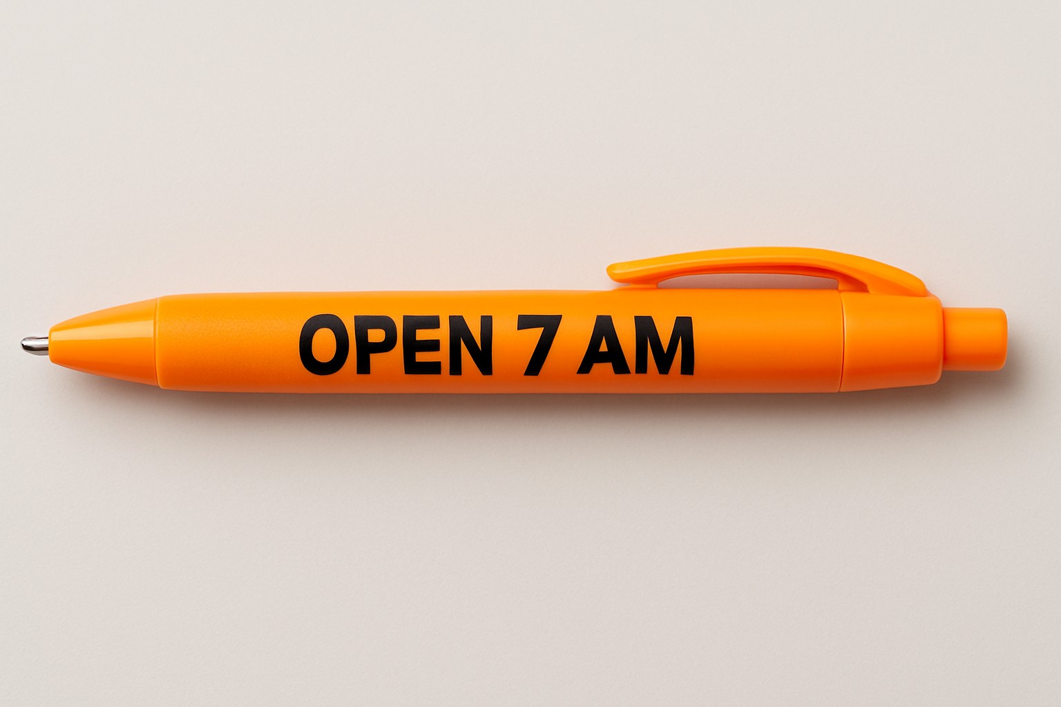 Orange retractable ballpoint pen with click plunger, clip, ballpoint tip, and OPEN 7 AM imprint